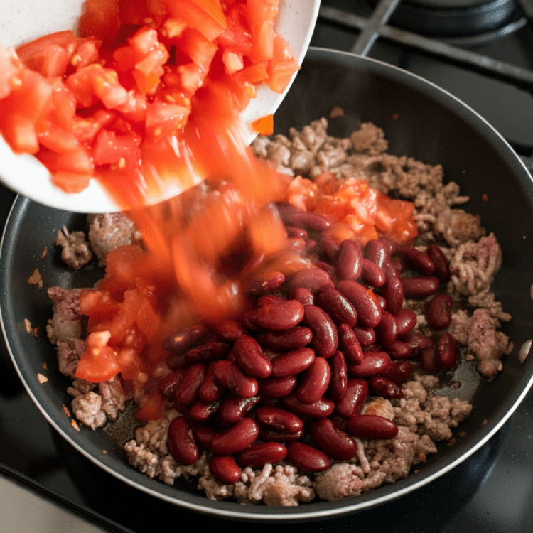 Adding diced tomatoes and beans to easy chili con carne, creating a rich and hearty mixture